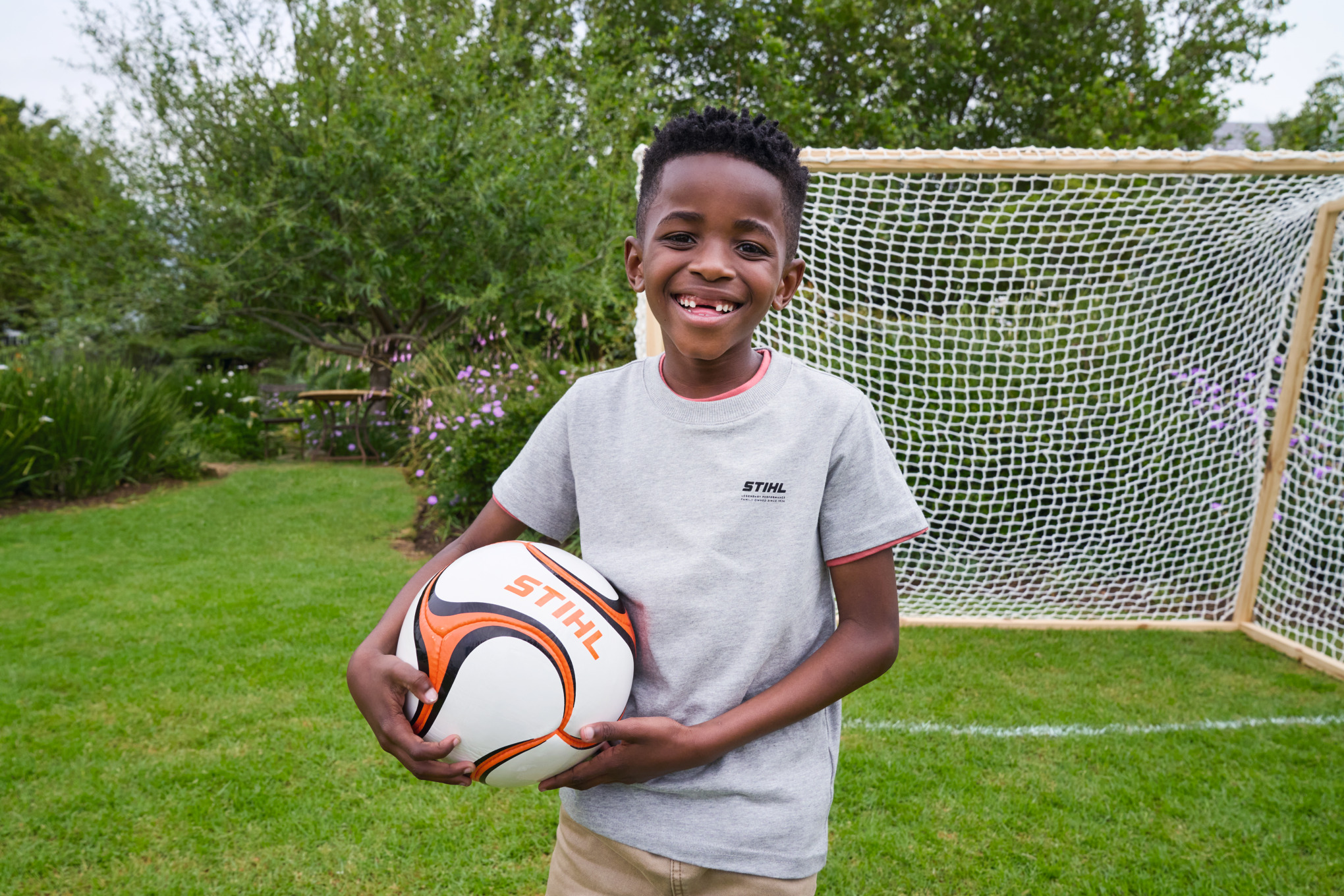 Un niño sostiene radiante una pelota de fútbol STIHL delante de la nueva portería