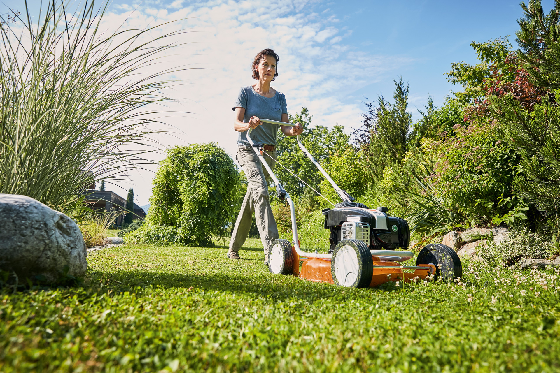 Mujer haciendo mulching con un cortacésped de gasolina STIHL RM 2 R sobre un terreno verde