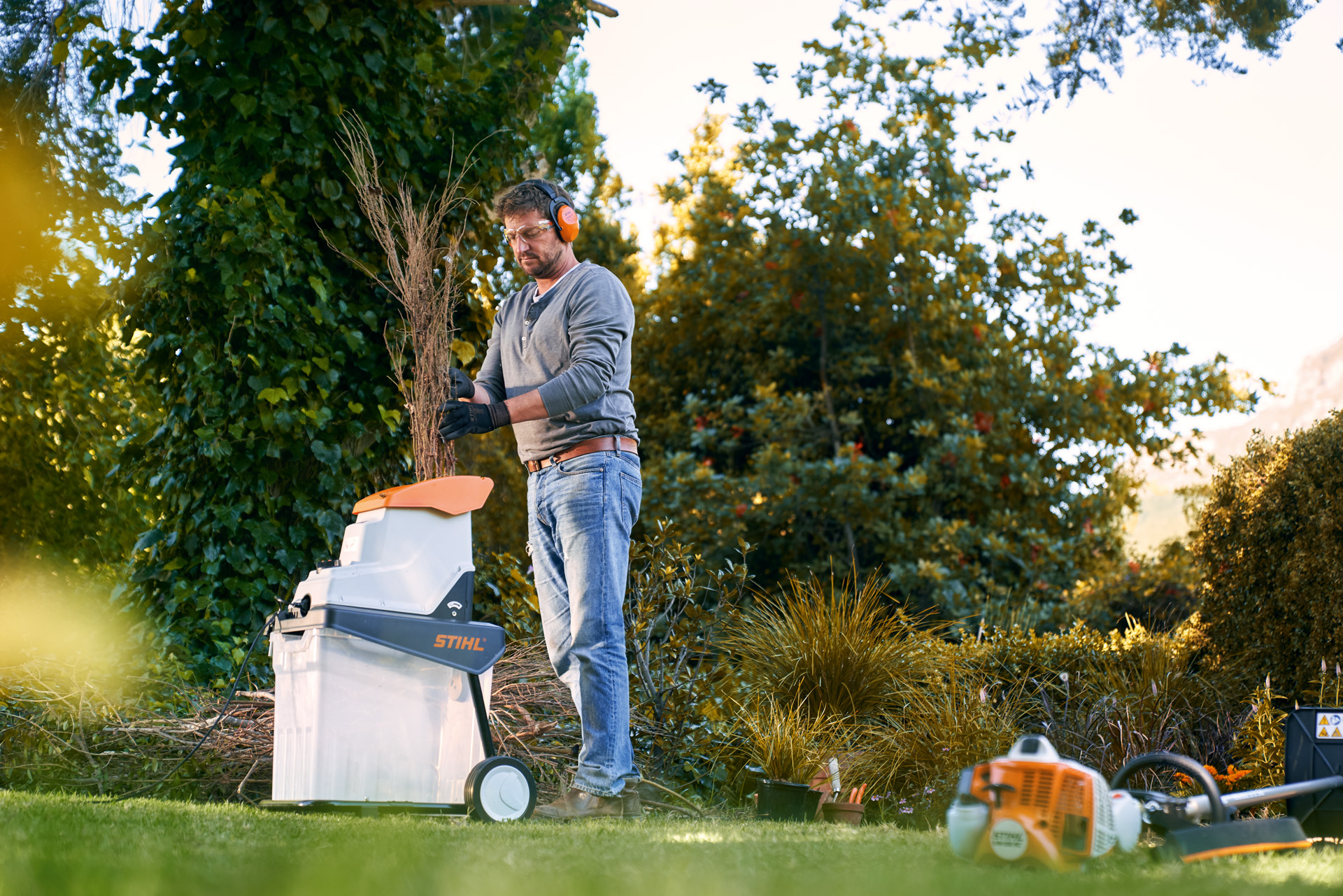 Un hombre con protección auditiva utiliza una biotrituradora eléctrica STIHL GHE 140 para hacer compost